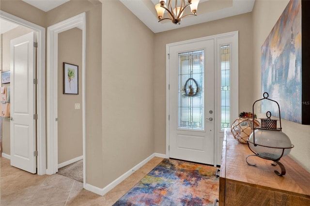 foyer entrance with light tile patterned floors, baseboards, and an inviting chandelier