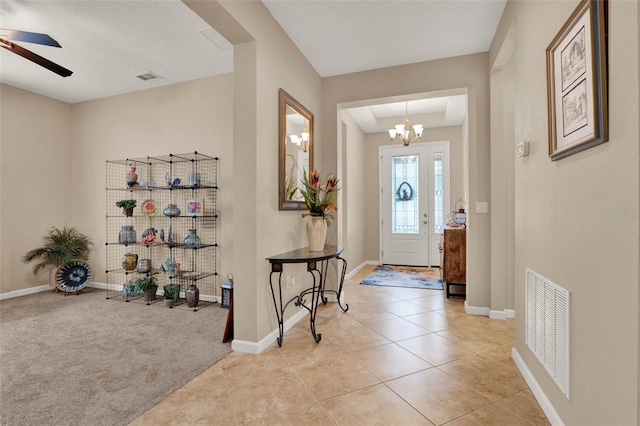foyer with ceiling fan with notable chandelier, light tile patterned flooring, baseboards, and visible vents