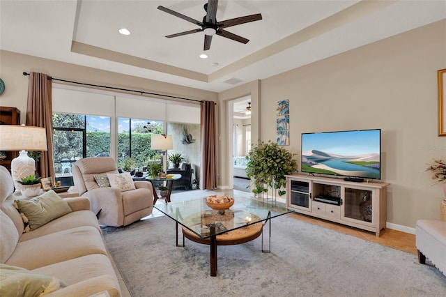 living room with a tray ceiling, ceiling fan, visible vents, and recessed lighting