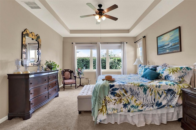 bedroom featuring carpet, visible vents, a tray ceiling, and baseboards