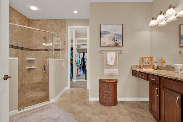 full bathroom with vanity, baseboards, a stall shower, a spacious closet, and tile patterned floors