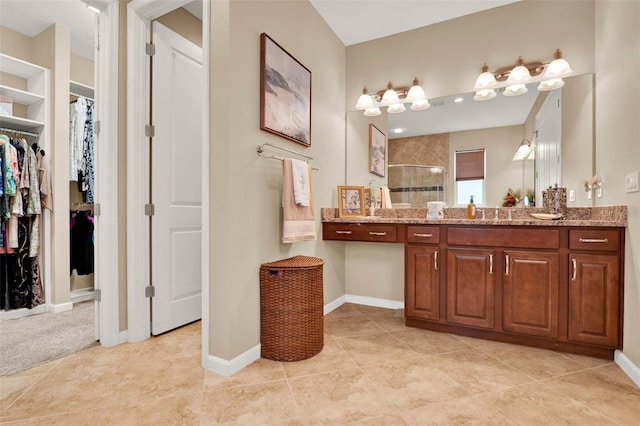 full bathroom featuring vanity, baseboards, a stall shower, a spacious closet, and tile patterned flooring