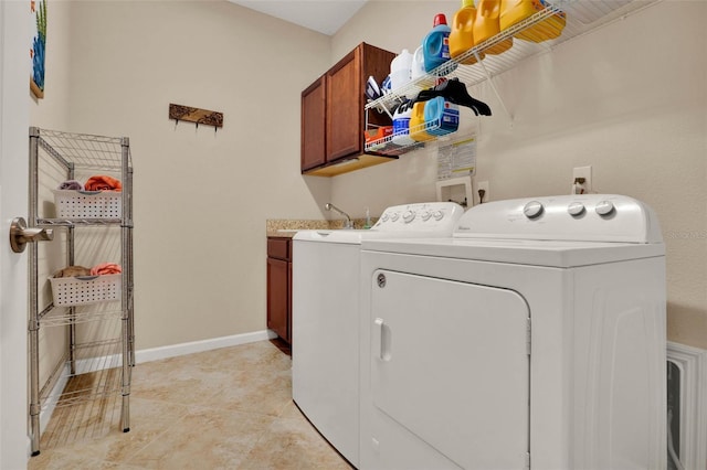 clothes washing area with light tile patterned flooring, baseboards, cabinet space, and washer and clothes dryer