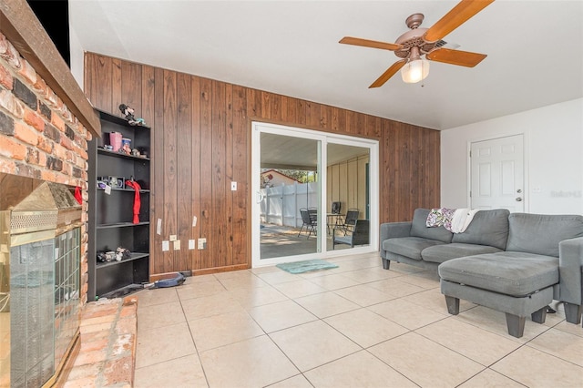 living area featuring light tile patterned floors, wooden walls, and ceiling fan