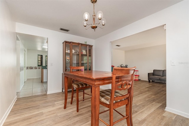 dining space featuring a notable chandelier, baseboards, light wood-style floors, and visible vents