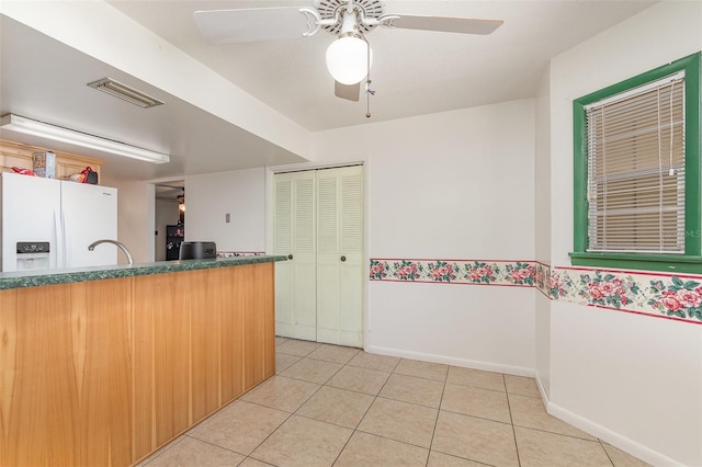 interior space featuring baseboards, visible vents, white refrigerator with ice dispenser, ceiling fan, and light tile patterned floors
