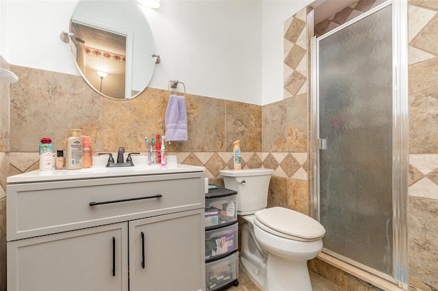 bathroom featuring vanity, toilet, a stall shower, and tile walls