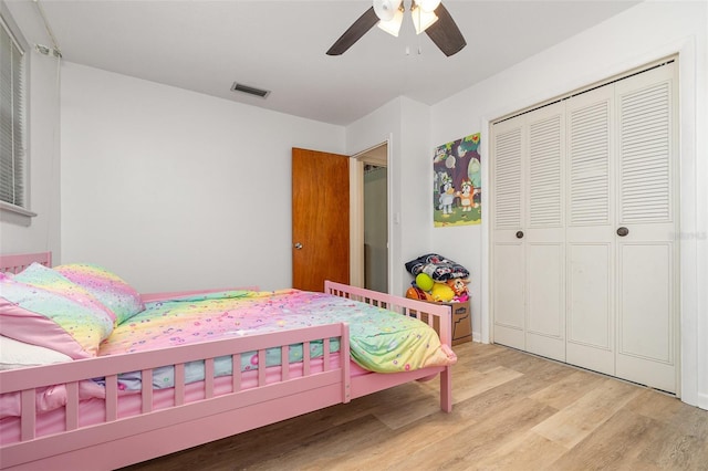 bedroom with light wood-style floors, visible vents, a ceiling fan, and a closet