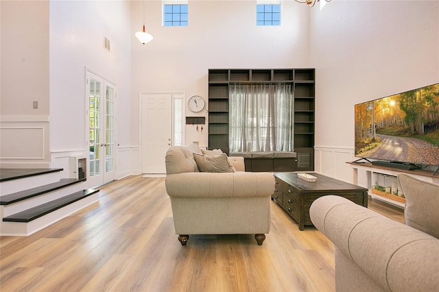 living area featuring a decorative wall, visible vents, and a high ceiling