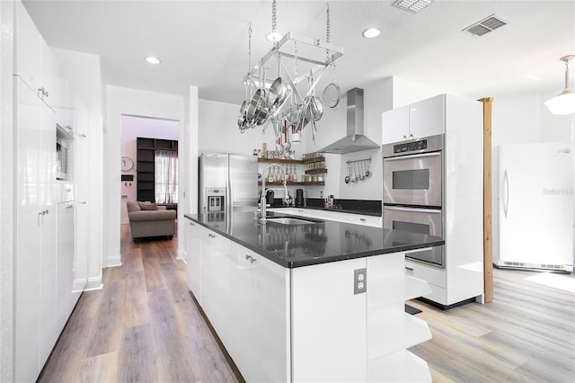 kitchen featuring wall chimney exhaust hood, open shelves, visible vents, a sink, and stainless steel appliances