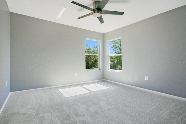 carpeted empty room featuring a textured wall, ceiling fan, and baseboards