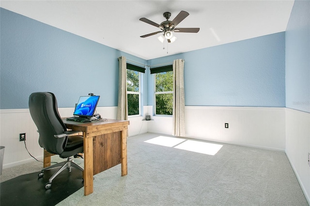 carpeted office space featuring a ceiling fan and wainscoting
