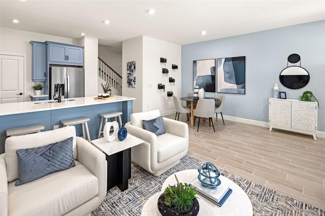 living room featuring recessed lighting, stairway, light wood-style flooring, and baseboards