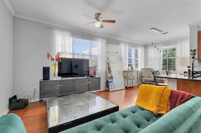 living area with crown molding, ceiling fan, baseboards, wood finished floors, and visible vents