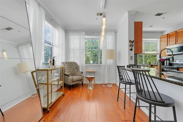 interior space with crown molding, baseboards, light wood-style flooring, and visible vents