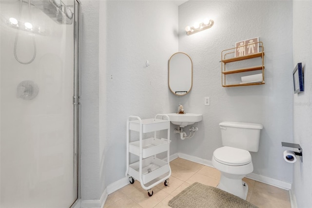 bathroom with toilet, baseboards, a shower stall, and tile patterned flooring
