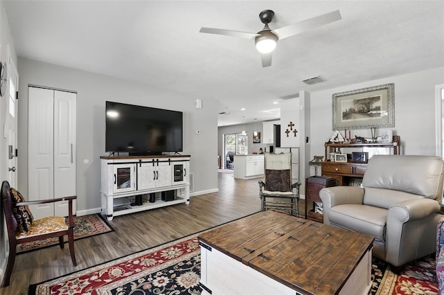 living area featuring baseboards, wood finished floors, visible vents, and a ceiling fan