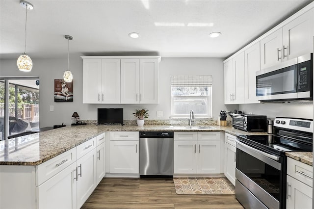 kitchen with a peninsula, appliances with stainless steel finishes, a sink, and a wealth of natural light