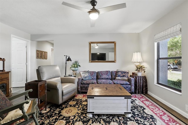 living room featuring wood finished floors, a ceiling fan, and baseboards