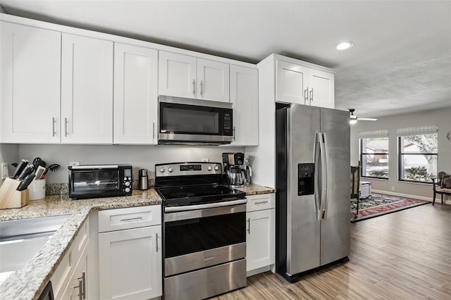 kitchen featuring a toaster, stainless steel appliances, light wood-style flooring, white cabinets, and recessed lighting