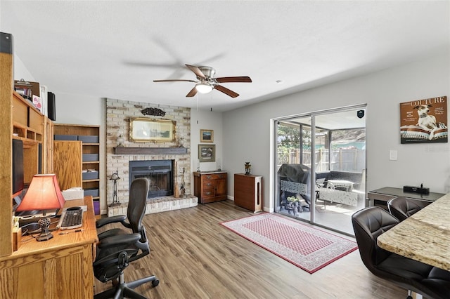 office featuring wood finished floors, a brick fireplace, and a ceiling fan