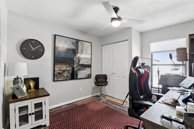 home office with a textured ceiling, baseboards, and ceiling fan