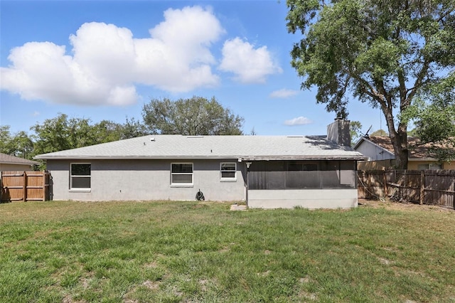 rear view of property featuring a fenced backyard, a sunroom, a yard, and stucco siding