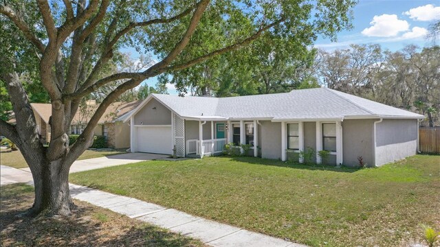 ranch-style house featuring an attached garage, a front lawn, covered porch, and concrete driveway