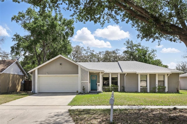 ranch-style house with concrete driveway, an attached garage, a front lawn, and stucco siding