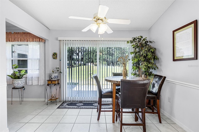 dining area with baseboards, a textured ceiling, light tile patterned flooring, and ceiling fan