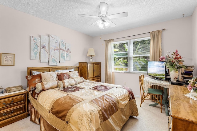 bedroom featuring a ceiling fan, light carpet, and a textured ceiling