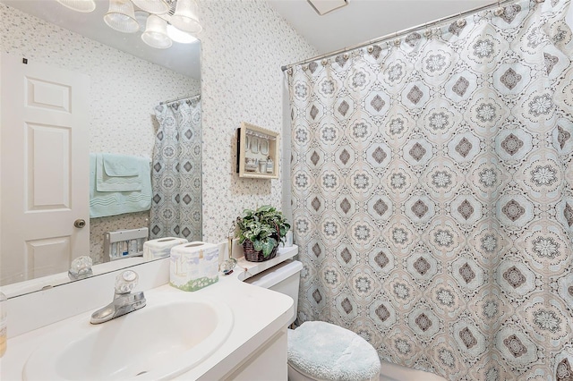 bathroom featuring toilet, curtained shower, vanity, and wallpapered walls