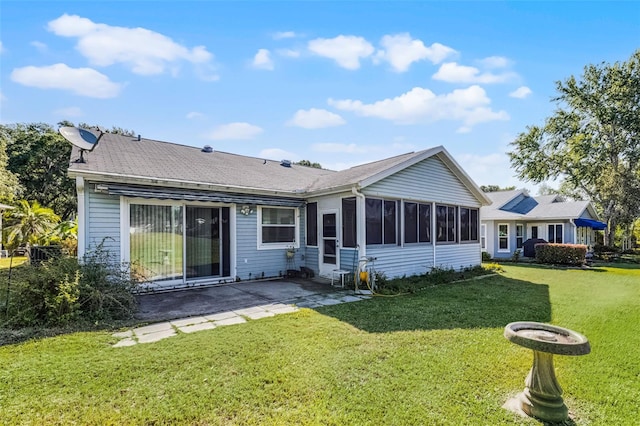 rear view of property with a yard, a patio, and a sunroom