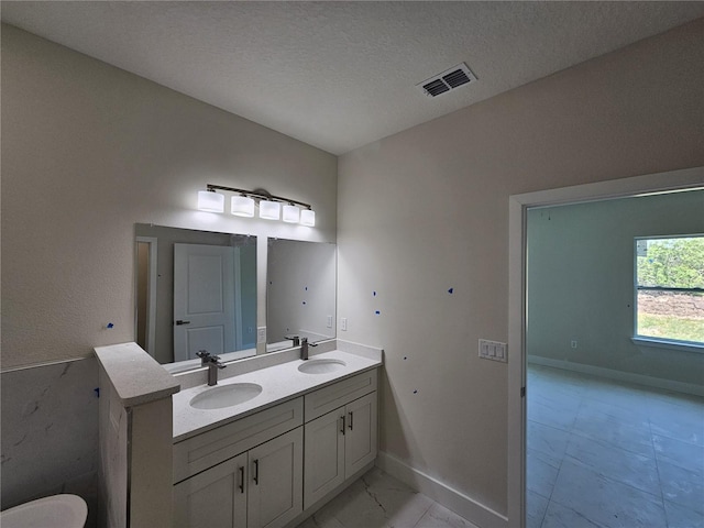 2310 Logsdon St, North Port, FL 34287 - bathroom with marble finish flooring, double vanity, baseboards, and a textured ceiling