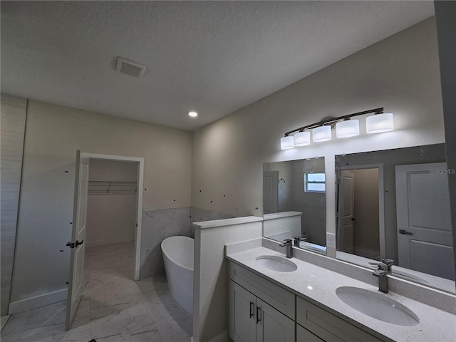 2310 Logsdon St, North Port, FL 34287 - bathroom featuring marble finish floors, double vanity, a freestanding bath, a walk in closet, and recessed lighting