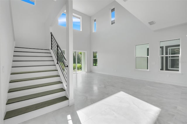 3024 Kensington Ave, Davenport, FL 33837 - unfurnished living room featuring baseboards, a high ceiling, stairs, visible vents, and marble finish floor