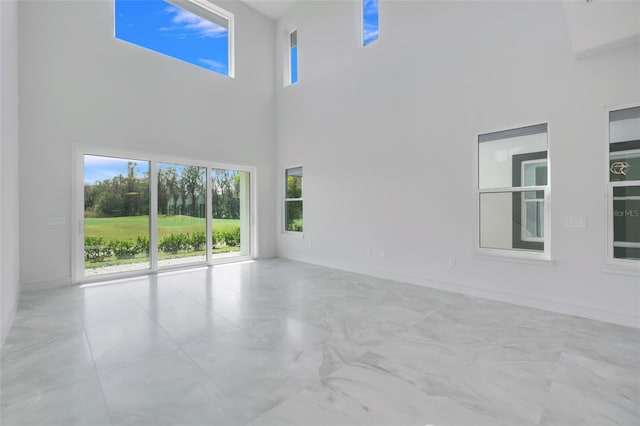 3024 Kensington Ave, Davenport, FL 33837 - unfurnished living room featuring baseboards, a towering ceiling, and a healthy amount of sunlight