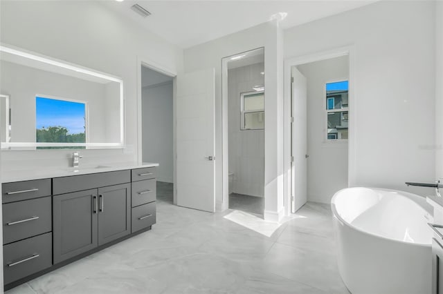 3024 Kensington Ave, Davenport, FL 33837 - bathroom featuring visible vents, baseboards, a soaking tub, vanity, and marble finish floor