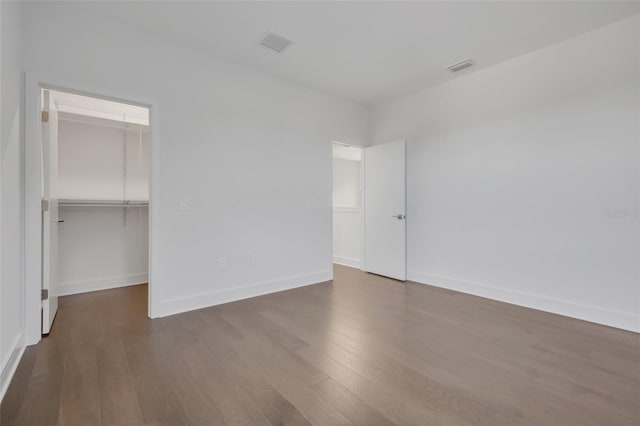 3024 Kensington Ave, Davenport, FL 33837 - unfurnished bedroom featuring dark wood-type flooring, baseboards, a walk in closet, and visible vents