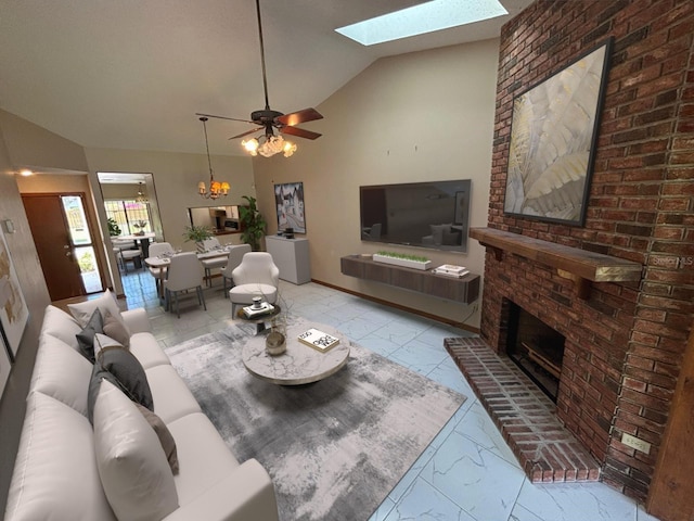 living room featuring marble finish floor, a skylight, a brick fireplace, high vaulted ceiling, and ceiling fan with notable chandelier
