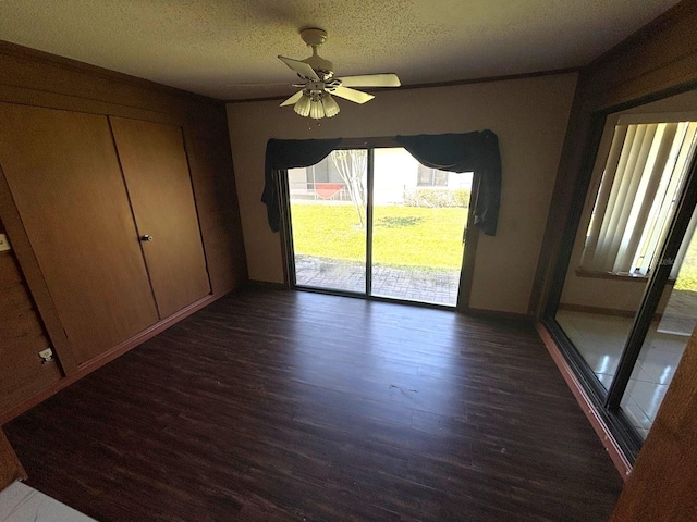 interior space featuring dark wood finished floors, baseboards, a ceiling fan, and a textured ceiling
