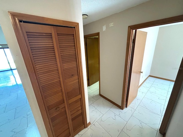 corridor featuring marble finish floor and baseboards