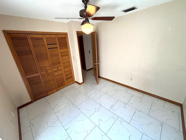unfurnished bedroom featuring baseboards, visible vents, marble finish floor, a closet, and ceiling fan