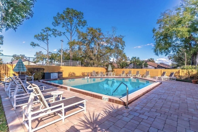 community pool with fence and a patio area