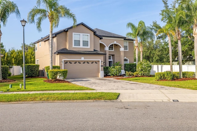 traditional-style home featuring fence, a garage, stucco siding, a front yard, and driveway
