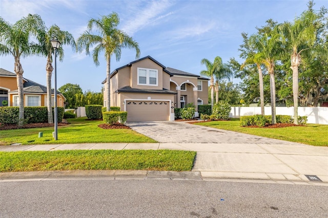 traditional home with fence, a front lawn, concrete driveway, an attached garage, and stucco siding