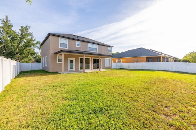 rear view of property featuring a lawn, a fenced backyard, a patio area, and stucco siding
