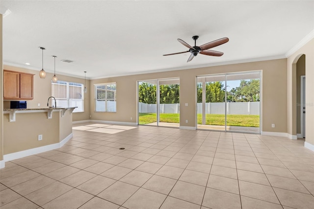 unfurnished living room featuring crown molding, ceiling fan, baseboards, and light tile patterned floors
