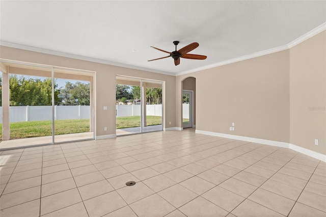 spare room with baseboards, ornamental molding, arched walkways, and ceiling fan