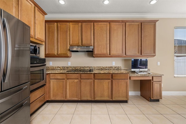 kitchen featuring brown cabinets, built in study area, under cabinet range hood, ornamental molding, and stainless steel appliances